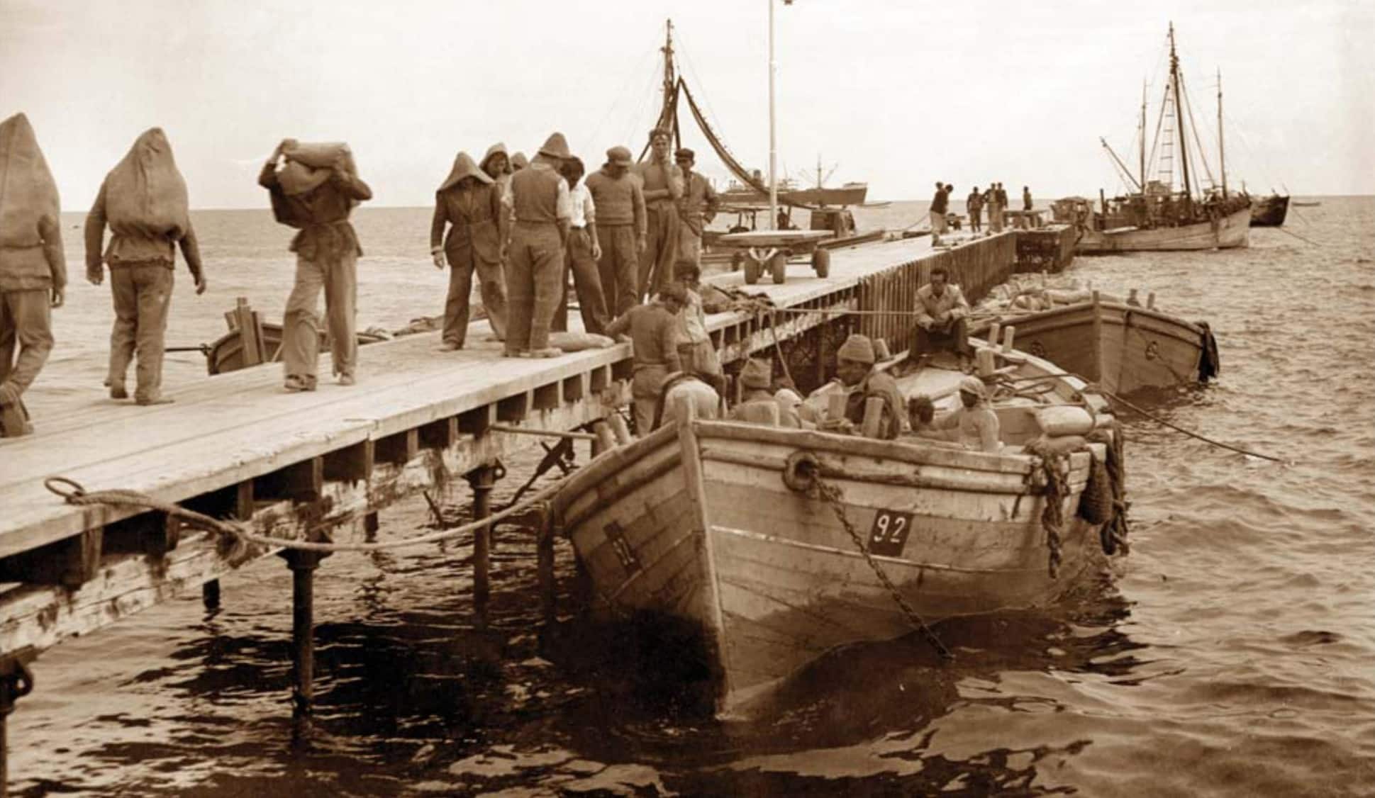 Dock workers loading cargo boats at Limassol's early customs pier